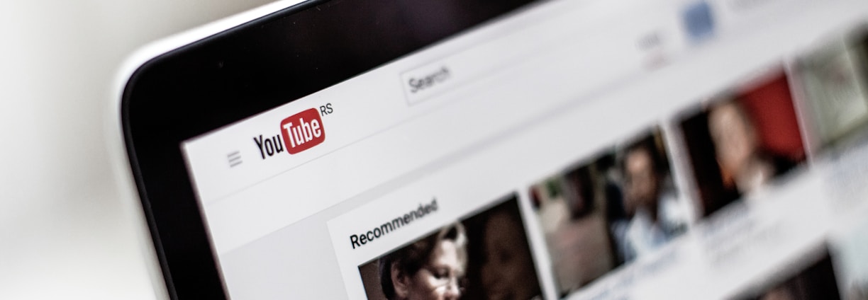 A close-up view of a computer screen displaying a YouTube page, showing the logo and multiple video thumbnails in a recommended section.